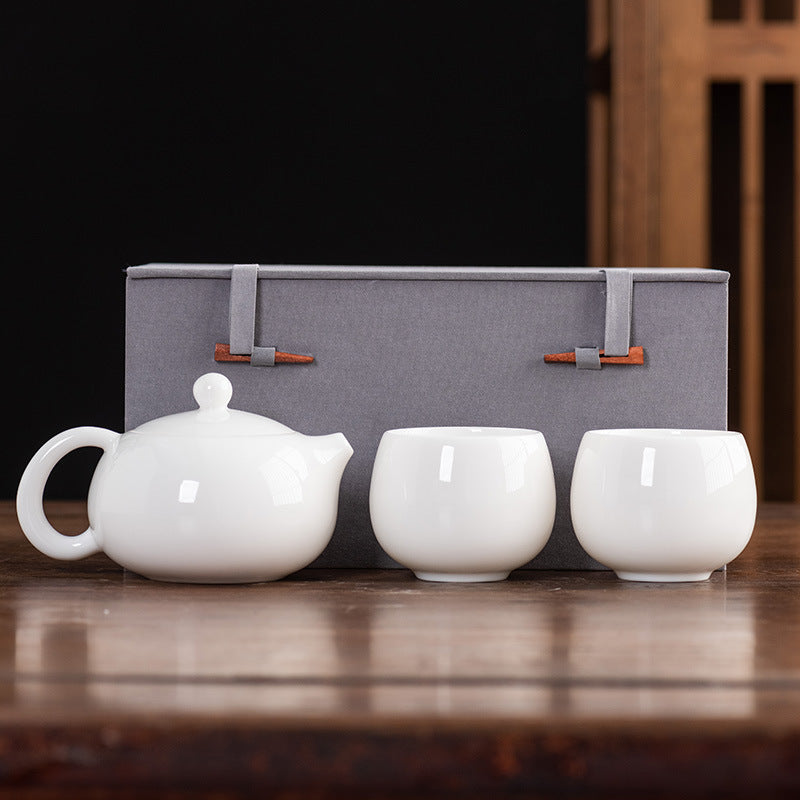 Front view of a Dehua Mutton Fat Jade Xishi teapot set with two matching Dragon Egg style teacups and a luxury gift box