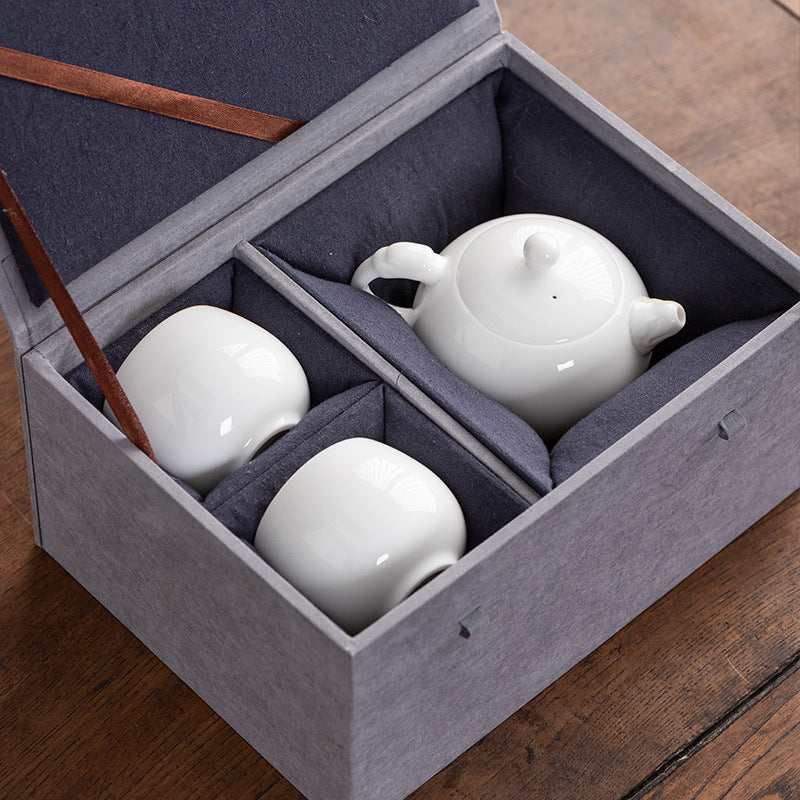 Bird's-eye view of a Dehua Mutton Fat Jade tea set securely nestled in a premium gift box, featuring one Xishi teapot and two matching teacups.