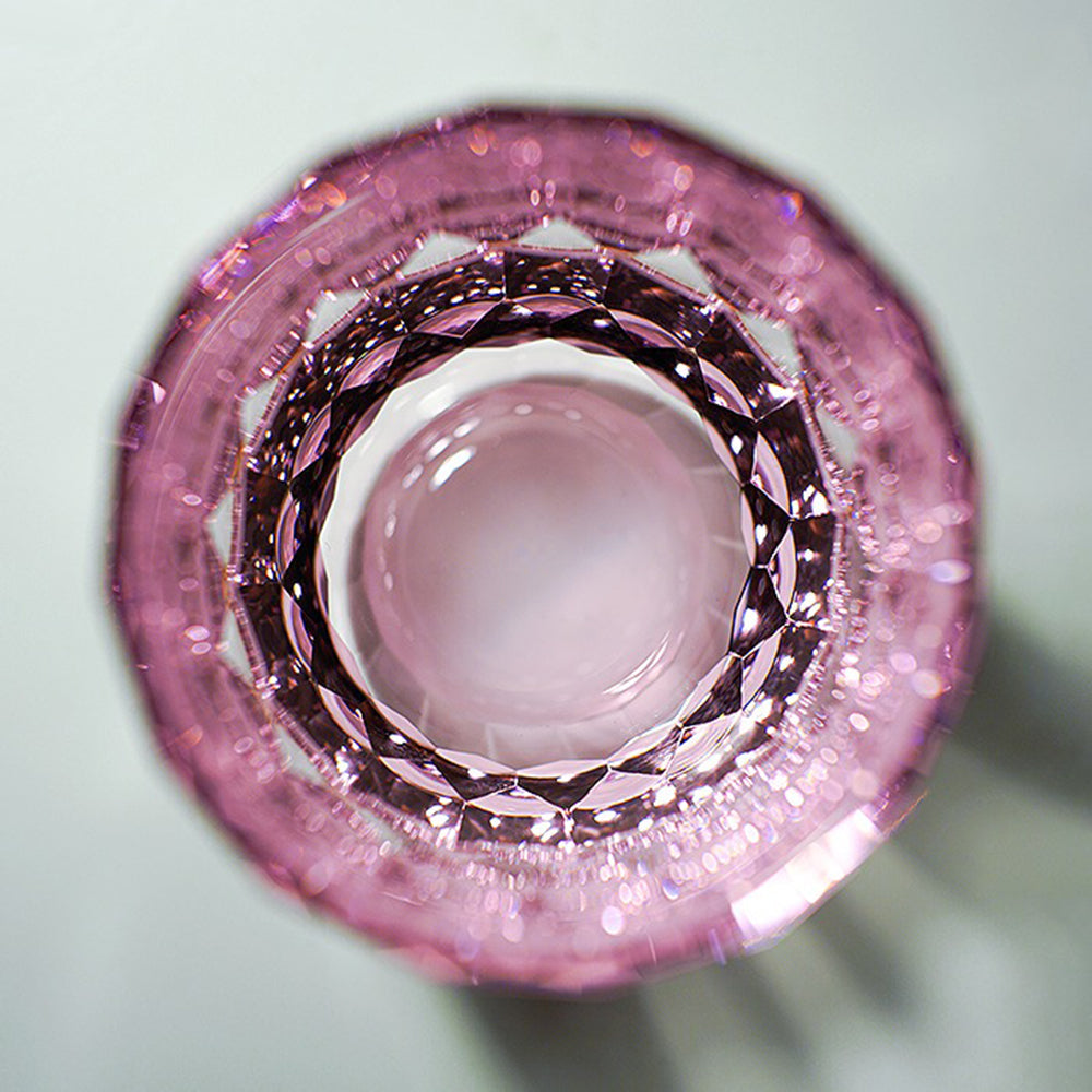 Top-down view looking into an Edo Kiriko inspired diamond-cut crystal glass, displaying concentric circles of pink light facets and optical clarity.
