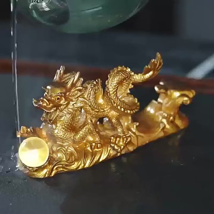 A demonstration video showing hot tea being poured over an Oriental Colour Changing Tea Pet shaped like a Chinese dragon with a crystal orb, revealing its vibrant color transformation on a Gongfu tea tray.